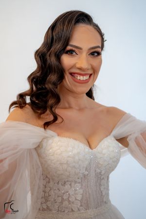 Close-up portrait of a glowing bride in an off-shoulder wedding gown.