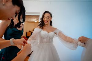 Wedding party preparations showing close-up details of a white bridal gown being fitted.