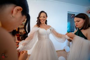 Wedding morning preparations showing bridesmaids in a bright room with a white dress.