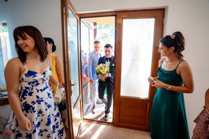 Wedding party getting ready in a sunlit room with wooden window frames.