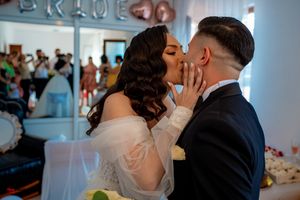 Celebratory moment at a wedding with decorative wall text visible in background.
