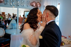 A tender moment shared between newlyweds during their wedding celebration with a 'BRIDE' sign visible in the background.