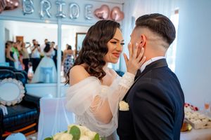 An intimate wedding moment captured as the couple shares a joyful embrace beneath decorative lettering.