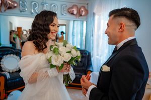 A romantic wedding moment captured as the couple interacts with a beautiful white rose bouquet.