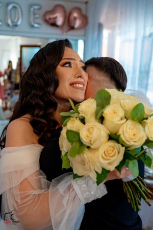 A radiant close-up moment at a wedding featuring cream roses and delicate off-shoulder dress details.