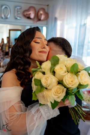 An intimate wedding moment with soft natural lighting and a classic white rose bouquet.