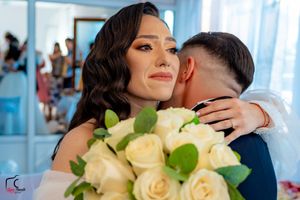A tender wedding embrace captured with soft lighting and cream roses.