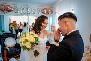 Romantic wedding moment captured in a room decorated with rose gold balloon letters spelling 'BRIDE'.