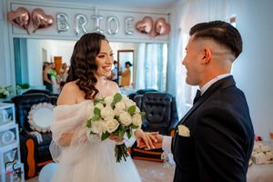 Elegant wedding scene with white roses and rose gold balloon decorations in the background.