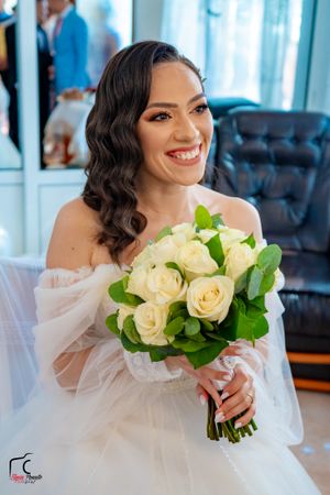 Elegant bridal portrait with a stunning white rose bouquet against blue curtains.