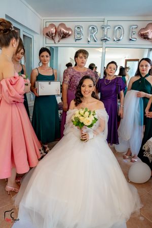 Wedding party gathering with bridesmaids in colorful dresses and elegant white decor.