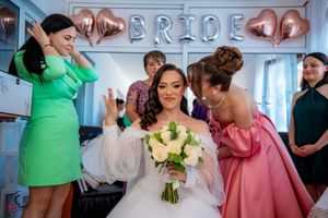 Wedding party gathered in a bright room with mixed pastel and jewel-toned attire.