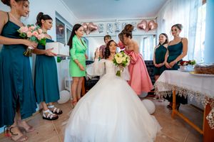 Wedding party gathers in a bright room decorated with balloons and banners for pre-ceremony preparations.