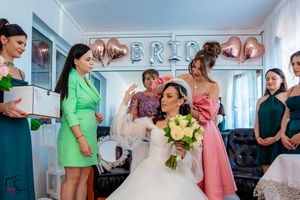 Wedding party members mingle and prepare in a decorated room with pink and silver balloon decor.