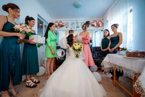 Wedding celebration preparations in a bright room with bridesmaids in colorful dresses.