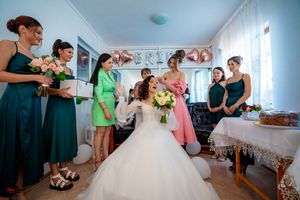 Wedding party members socialize in a decorated room with pink and silver balloon letters.