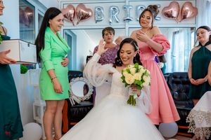 Bridal party members gather in a bright room with balloon decor and floral arrangements.