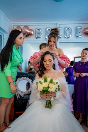 Wedding preparation showing bride in puffy white dress with yellow roses and bridesmaids in bright colors.