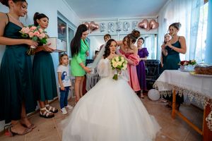 Bridal party in mixed colored dresses helping bride prepare for wedding ceremony.