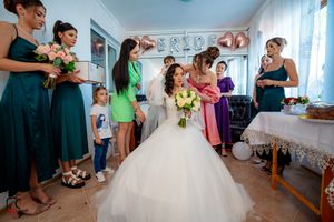 Wedding preparation scene with bridesmaids in various colored dresses assisting the bride.