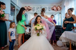 Bridal preparations in a sunlit room with bridesmaids in vibrant dresses helping the bride get ready.