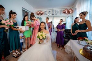 Wedding preparations scene with bridesmaids in colorful dresses assisting in a decorated room.