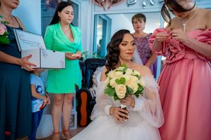 Bridesmaids in colorful dresses assist during pre-wedding preparations in a decorated room.