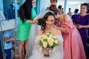 Joyful pre-wedding moment as attendants in bright dresses help with final preparations.