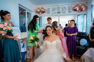Wedding preparation scene with attendants gathered around in colorful attire.