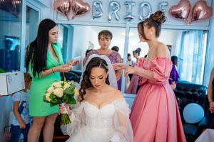 Pre-wedding preparations with attendants in bright green and pink dresses assisting the bride.