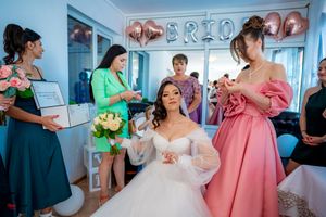 Wedding celebration scene with bridesmaids in pink dresses and decorative metallic balloons.