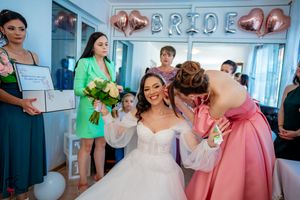 Wedding party members share joyful moment in room with metallic balloon decorations.
