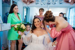Pre-wedding celebration with bridesmaids in pink and green attire under balloon decorations.