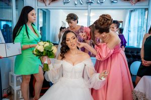 Bridal party celebrates in bright room with rose gold balloon decorations and signage.
