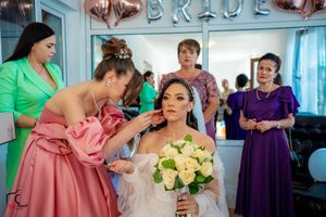 Bridesmaids in colorful dresses assist with makeup preparations before the ceremony.
