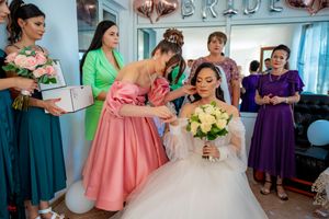 Wedding party assists with final touches while bride holds yellow bouquet.