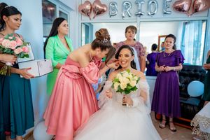 Bridal party members in jewel-toned dresses help with final wedding preparations.