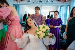 Candid moment during bridal preparation with attendants in colorful formal attire.