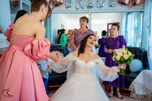 A joyful pre-wedding scene shows final makeup touches being applied to a bride in a white ballgown.
