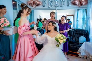Bridal party getting ready in a room decorated with pink balloons and blue walls.