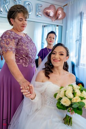Candid wedding moment showing bride with bouquet surrounded by purple-dressed attendants.