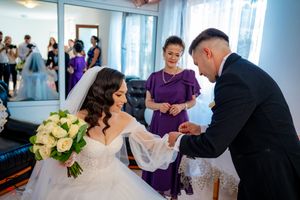 Intimate wedding ceremony moment captured in a room with sheer blue curtains and natural lighting.