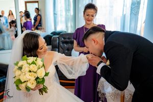 Wedding celebration with purple bridesmaid dresses and cream roses in a naturally lit room.