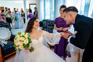 Wedding ceremony with purple and black attire in an elegantly decorated room with sheer curtains.