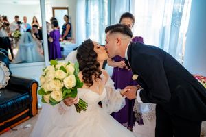 A romantic scene with formal attire and white bouquet against blue curtains.