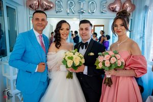 Wedding party members gather under decorative letters in a blue-walled room.
