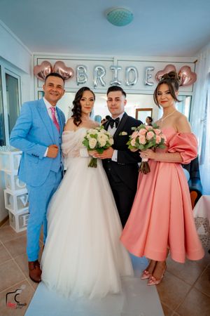 Wedding party poses in a room with blue walls and coral pink bridesmaid dresses.