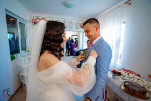 Candid wedding preparations in a room with light blue walls and white curtains.