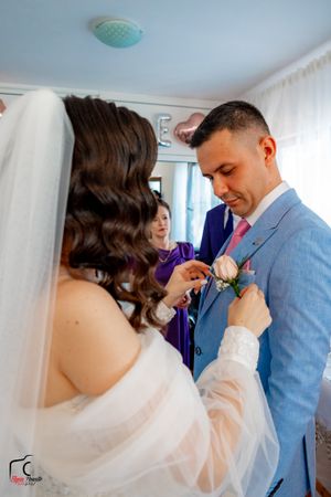 A sweet moment between wedding couple in a room with blue walls.