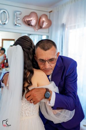 Emotional wedding moment captured in a room with decorative wall letters.